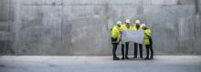 Group of engineers standing in front of a concrete wall at a building site